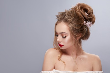 pretty blonde with wavy hairstyle and red lips looking downの写真素材