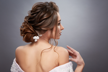 bride with pretty hairstyle touching her shoulder and looking sideways