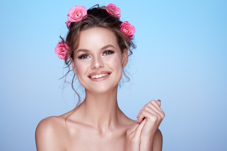 Gorgeous woman at blue studio background with flowersの写真素材