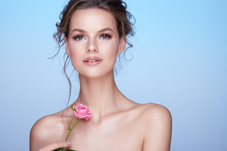 Gorgeous woman at blue studio background with flowersの写真素材