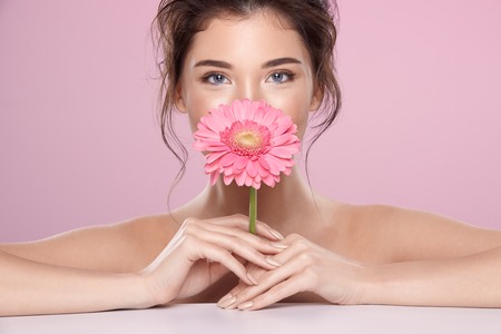 Woman at  pink studio background with flowersの写真素材