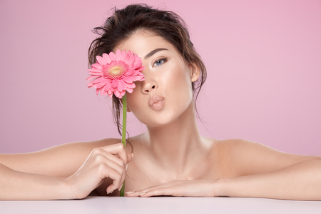 Woman at  pink studio background with flowersの写真素材