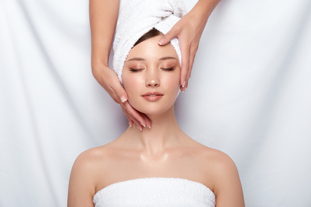 beauty master holding womans face that lying down on white, head and face treatment for women, client of spa theraphyの写真素材