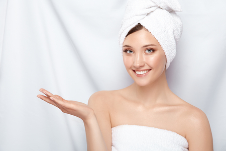 attractive young lady in bath towel on head pretending that she holding something on her arm, copy space, pretty girl keeps arm near shoulderの写真素材