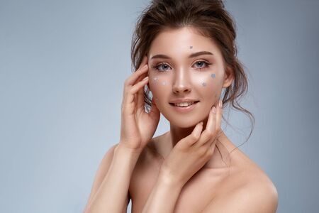 attractive model with perfect skin and natural flowers touching her face, woman with curls and shiny mua decorated with natural forget-me-notsの写真素材