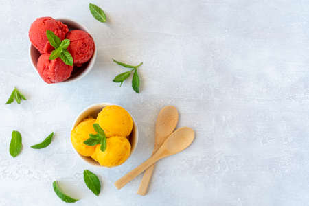 Ice cream scoops in bowls with strawberry and mango flavors. Top viewの写真素材
