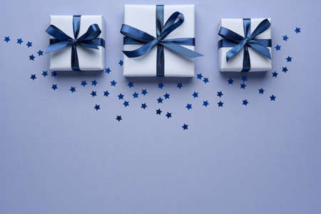 Gift boxes with ribbon and bow on blue background with confetti stars. Top view and space for text.の写真素材