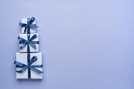 Stack of tree gift boxes on blue background. Top view, flat layの写真素材
