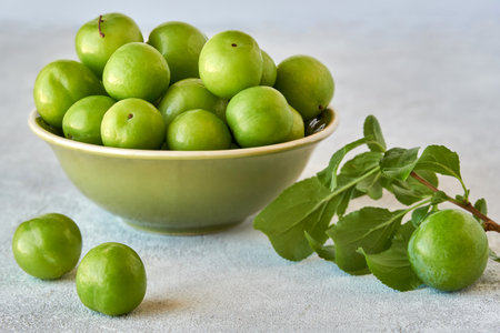 Green sour plum in ceramic bowlの写真素材