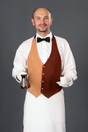 Waiter in uniform with percolator and cup of coffe. の写真素材