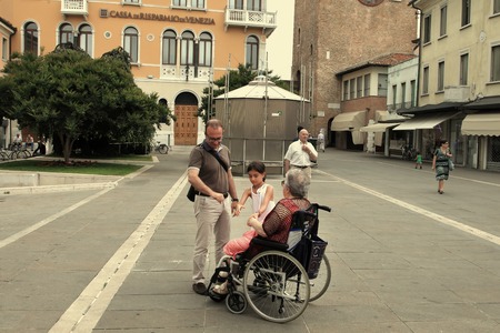VENICE, MESTRE-June 29, 2014: Disabled grandmother in a wheelchair and grandchild  on Piazza Erminio Ferretto in Italy. VENICE, MESTRE-June 29, 2014のeditorial素材