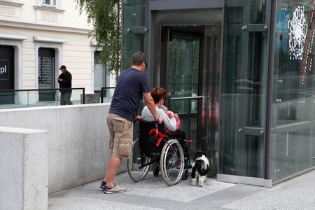 LJUBLJANA, SLOVENIA -  JUNE 28, 2014: Husband and wife in a wheelchair with a dog come in passenger lift. LJUBLJANA, JUNE 28, 2014のeditorial素材