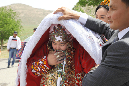 Kov-Ata, Turkmenistan - April 30, 2017: Turkmen national wedding in the village of Kov-Ata. The groom shows his bride's face to the guests.  Turkmenistan - April 30, 2017.のeditorial素材