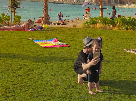 La Mer in Dubai, UAE - May 06, 2018: Mom with baby on the beach La Mer at sunset.  It is a new beachfront district with shopping and restaurants in Jumeirah. DUBAI, UAE -May 06, 2018 .のeditorial素材