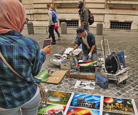 Rome, Italy - April 9, 2018 : Street artist - young man painting with spray pictures of Colosseum on pedestrian walk of Via delle Muratte leading to Fontana di Trevi in Rome, Italyのeditorial素材