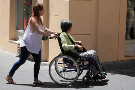 Aix-en-Provence, FRANCE - JULY 1, 2019: Young woman pushing a old woman in a wheelchair.のeditorial素材