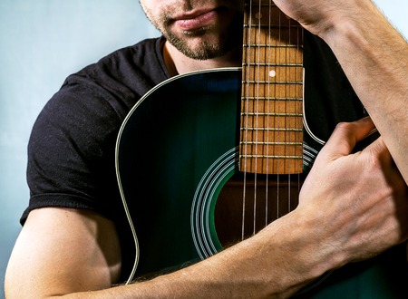 guitarist holding an acoustic guitar on a light backgroundの写真素材