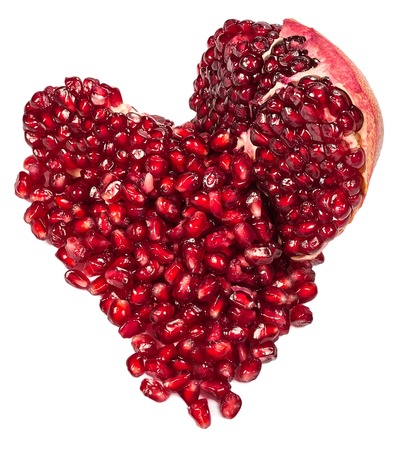 pomegranate and seeds in a heart-shaped  isolated on a white backgroundの写真素材