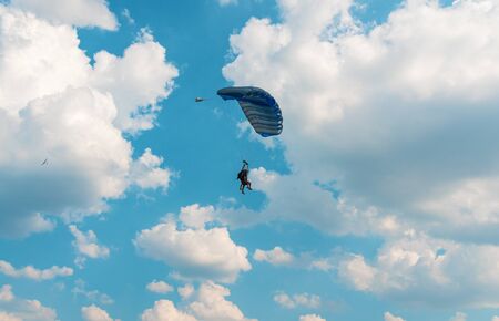 Two men flying in the blue sky using parachuteの写真素材