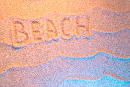 BEACH lettering on sand with wave and neon light. Minimal exotic vacation and travel concept, Flat lay top view copy spaceの写真素材