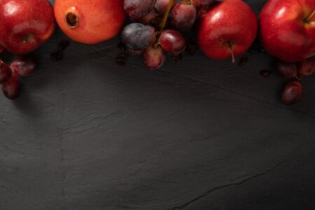 Red fruits background, dark stone slake plate with copy space. Flat lay top view. Summer abstract creative trendy fresh concept.の写真素材