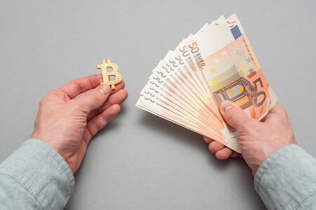Bitcoin buy and sell concept. Man holds bitcoin and euro money.