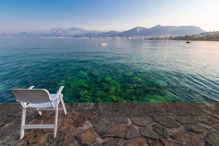 symbol of loneliness, lonely chair in the Crete island beach in sunset time. Greece vacation, copy space.の写真素材