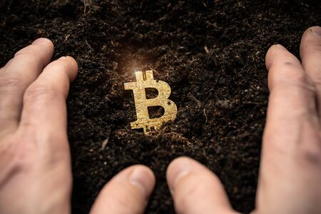 Bitcoin hold concept. Cryptocurrency stored in the ground - saving symbol. A man buries, hides bitcoins.の写真素材