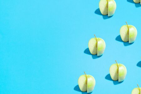 Summer abstract trendy fresh concept. green sliced Apple pattern on bright light blue background, copy space. Minimal flat lay food texture.の写真素材
