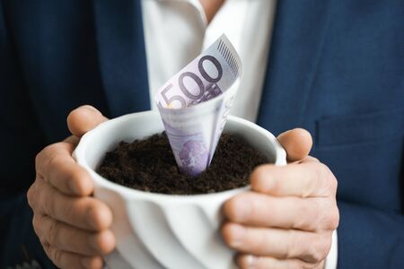 500 euro growing money in in flowerpot. Investment And Interest Concept. businessman protects growing investments.の写真素材