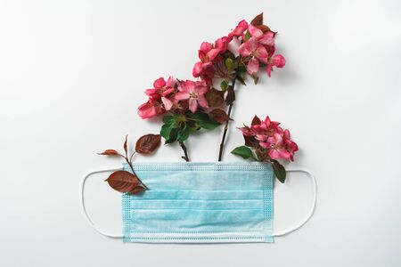 Anti-virus medical mask and spring red flowers. Stop Coronavirus pandemic symbol. defeating the virus idea. Top view copy space, flat lay. Covid-19 victory concept.の写真素材