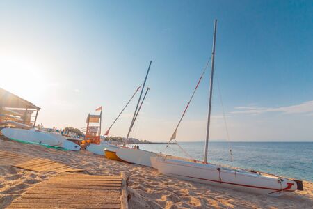 Low season empty beach with sun loungers and straw umbrellas. in Crete town Hersonissos Day foto. Greece vacation.の写真素材