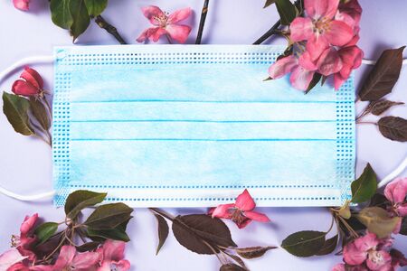 Anti-virus medical mask and spring red flowers. Stop Coronavirus pandemic symbol. defeating the virus idea. Top view copy space, flat lay. Covid-19 victory concept.の写真素材