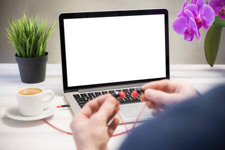 Home relax concept, a man listens to music at home. Laptop computer white blank screen on work table. Copy space, home office workspace concept, laptop mockup.の写真素材