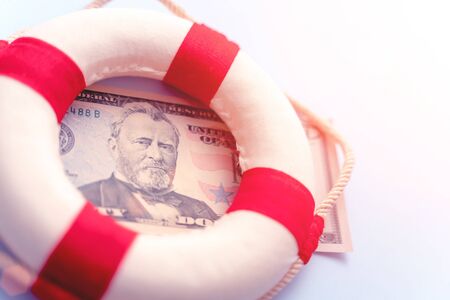 Abstract fast emergency rescue business financial economics crisis. Concept of fix economy financial crisis in USA or global world economy. Lifebuoy on US dollar paper banknote bill background.の写真素材