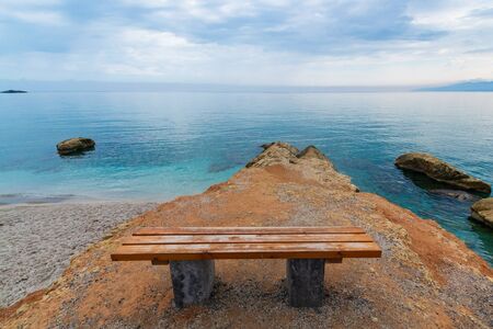 symbol of loneliness, lonely bench in the Crete island beach in sunset time. Greece vacation, copy space.の写真素材