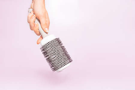 Had holding hair brush tool under trendy color background with copy space and soft light. Stylish Professional Barber hair cut tools, Hairdresser salon concept, Haircut accessories.の写真素材