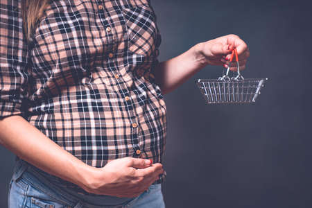 pregnancy shopping, motherhood, people and expectation concept - pregnant woman with shopping cart touching her big belly. Toned imageの写真素材