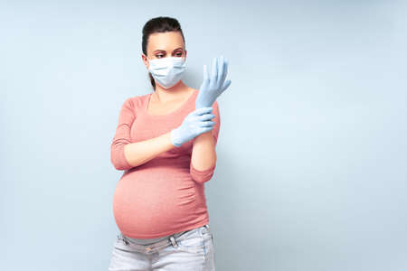 Yang woman put on blue gloves. Healthcare and Infection concept. Woman in Medical Face Mask and blue gloves against flu and viruses, copy space. High resolution.の写真素材