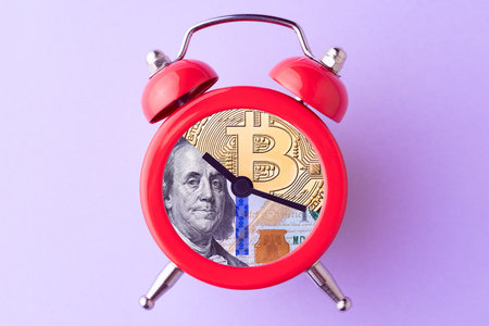 Bitcoin and US dollar bill in alarm clock. Concept of deadline to invest in cryptocurrency. Time to...