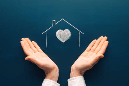 Insurance house icon and care concept. Female tender hands with a home symbol drawing on chalkboard.の写真素材