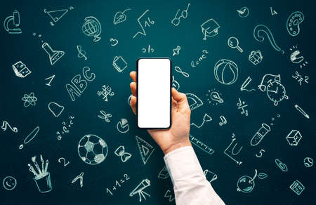 School icons set drawing on chalkboard and hand holding smartphone with blank screen for websites or...