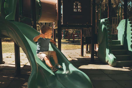 Child on a slide. Boy playing in outdoor playground. Kid play on school or kindergarten yard....