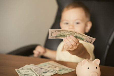 Smart happy child boy holding dollar banknote saving in piggy bank. Saving money in a piggy bank, learning about saving. Money, finances, insurance, and people conceptの写真素材