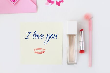 Flat lay: yellow paper, pink envelope, pen, pompom, perfume, lipstick, confetti hearts, lip print, i love you text. Making postcard in envelope for Valentine's Day.Do it yourself.Photo from the seriesの写真素材