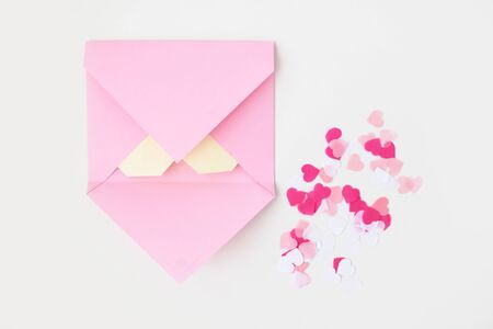 Flat lay: pink hand made envelope, confetti hearts, origami yellow heart made of paper for notes. Making postcard for Valentine's Day. Do it yourself. Photo from the seriesの写真素材
