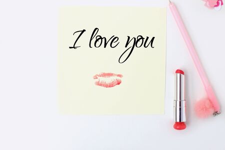 Flat lay: yellow paper, pink pen, pompom, lipstick, confetti hearts, lip print, i love you text. Making postcard in envelope for Valentine's Day.Do it yourself.Photo from the seriesの写真素材