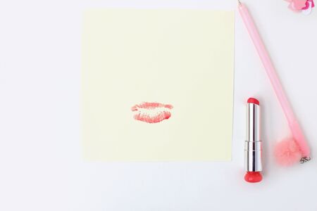 Flat lay: yellow paper, pink pen with pompom, lipstick, confetti hearts, lip print. Making postcard in envelope for Valentine's Day. Do it yourself. Photo from the seriesの写真素材