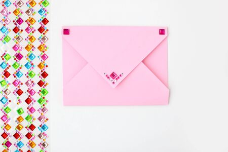 Pink envelope and a set of multi-colored rhinestones for decoration on white background. Making postcard in envelope for Valentine's Day. Do it yourself. Photo from the seriesの写真素材