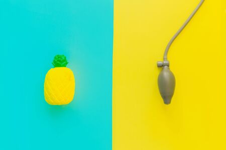 Flat lay stress and antistress: toy squish yellow pineapple, blood pressure monitor. Bright blue background.Compressing, soft, squeezable items to relieve, problems, anxieties, worries.Summer concept.の写真素材